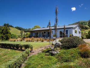 a house in the middle of a yard at Paddock House - Motueka Holiday Home in Motueka