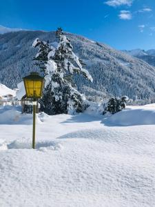 Villa Emilia في كالز ام غروغلوكنير: مصباح في الثلج بجانب شجرة مغطاة بالثلج