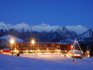 un edificio en la nieve por la noche con montañas cubiertas de nieve en Charmant studio rénové 2 personnes - chez Lulu en Le Corbier