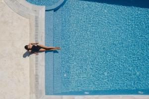 a woman laying on the edge of a swimming pool at White Dunes Luxury Boutique Hotel in Santa Maria
