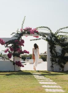 kobieta chodząca pod łukiem z kwiatami w obiekcie White Dunes Luxury Boutique Hotel w mieście Santa Maria