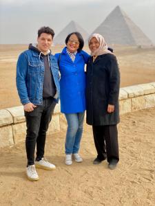a group of three people standing in front of the pyramids at Four pyramids Guest house pyramids View in Cairo