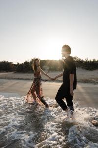 a man and woman walking in the water on the beach at White Dunes Luxury Boutique Hotel in Santa Maria