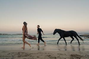 a man and a woman walking a horse on the beach at White Dunes Luxury Boutique Hotel in Santa Maria