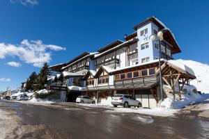 un grand bâtiment avec des voitures garées devant lui dans l'établissement Sporting Hotel, à Passo del Tonale