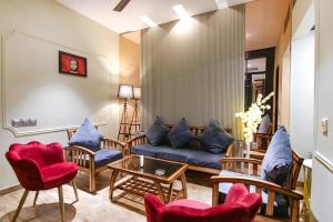 un soggiorno con divano blu e sedie di FabHotel Prime K9 Crown a Ludhiana