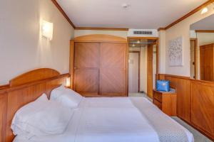 a bedroom with a large white bed with a wooden headboard at Hotel Caesius Thermae & Spa Resort in Bardolino