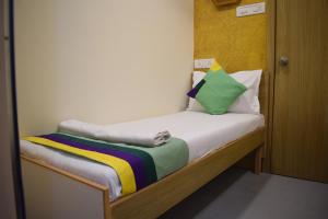 a small bed with a colorful blanket on it at ZEST STAYS - IIT in Mumbai