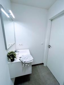 een witte badkamer met een wastafel en een spiegel bij Éclat Bruxellois - Modernité & Vue - Proche Atomium! in Brussel