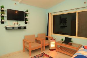 a living room with a tv and a chair and a table at The Pahadi Nest Mukteshwar in Mukteshwar