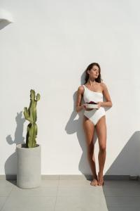 kobieta w białej sukience stojąca obok kaktusa w obiekcie White Dunes Luxury Boutique Hotel w mieście Santa Maria