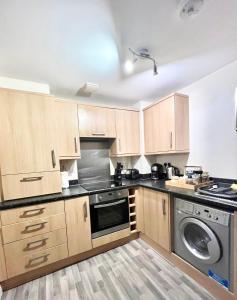 a kitchen with wooden cabinets and a washing machine at Ashford Modern Apartments, central location wt parking great location for holidays! in Ashford