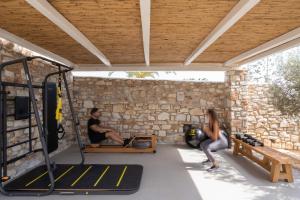 a man and a woman sitting on a bench under a stone wall at White Dunes Luxury Boutique Hotel in Santa Maria