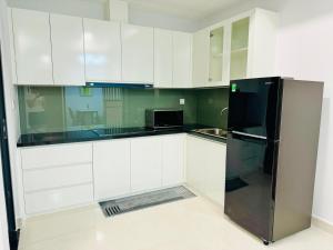 a kitchen with white cabinets and a black refrigerator at Căn hộ The Rivana 2 phòng ngủ đầy đủ tiện nghi tại Thuận An, Bình Dương in Thuan An +20 photos