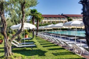 a pool with white umbrellas and chairs next to a resort at Hotel Caesius Thermae & Spa Resort in Bardolino
