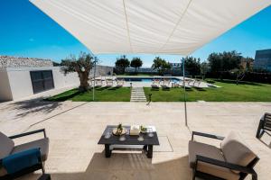 a patio with a table and chairs under a white umbrella at Villa Torre Molino - IsulaTravel in Modica