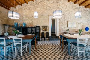 a dining room with tables and chairs and a stone wall at Villa Torre Molino - IsulaTravel in Modica