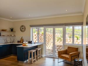 uma cozinha com armários azuis, uma mesa e uma cadeira em Pincushion Heights em Brenton-on-Sea