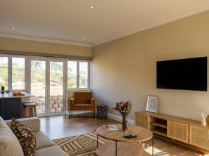 a living room with a couch and a tv on the wall at Pincushion Heights in Brenton-on-Sea