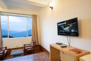 um quarto com uma televisão de ecrã plano na parede em Hotel Blue Poppy em Gangtok