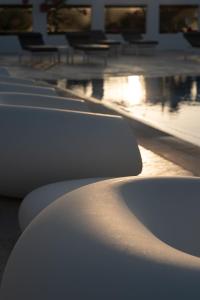 a row of white benches sitting next to a pool at White Dunes Luxury Boutique Hotel in Santa Maria