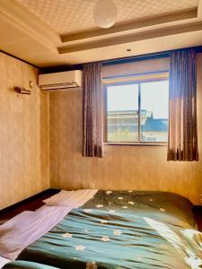 a bed in a room with a window at T&T Fujiyama Guest House in Fujiyoshida