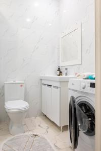 a white bathroom with a toilet and a washing machine at One Bedroom Apartment Near Arbat In The Center of Almaty in Almaty