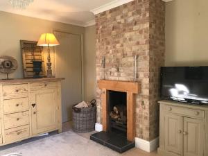 a living room with a brick fireplace with a television at Rural house 2BR 4 person 20 min f/beach, Rolvenden in Rolvenden