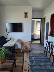 a living room with a table and a tv on a wall at A Felicidade Mora Aqui!!!! in Novo Hamburgo