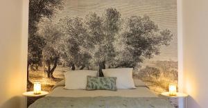 ein Bett mit zwei Kissen und einem Gemälde an der Wand in der Unterkunft Maison d'hôtes La Bignone in Laudun