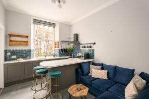 Il comprend une cuisine et un salon doté d'un canapé bleu. dans l'établissement Vibrant Leith Flat, à Édimbourg
