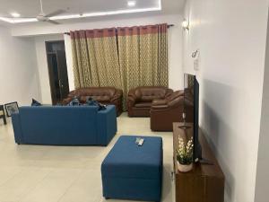 a living room with a couch and a blue ottoman at Colombo Reach Appartment By Layathraa in Kaduwela