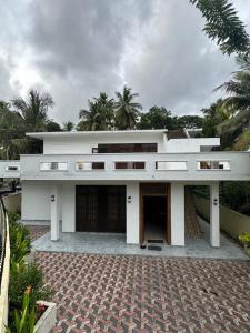 a large white building with a courtyard and palm trees at Colombo Reach Appartment By Layathraa in Kaduwela