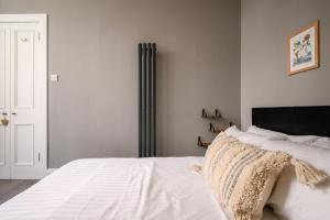 a bedroom with a white bed with a black headboard at Vibrant Leith Flat in Edinburgh