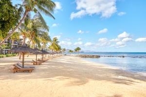 a beach with benches and palm trees and the ocean at InterContinental Mauritius Resort Balaclava Fort, an IHG Hotel in Balaclava