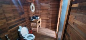łazienka z toaletą i drewnianą ścianą w obiekcie Umah Nanda w mieście Kubupenlokan