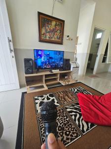 a person holding a camera in a living room with a television at Kavilla2 Regency in Karangploso