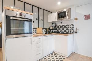 eine Küche mit weißen Schränken und einer Mikrowelle in der Unterkunft Le Saint Vincent - 4/6P - 300m de la plage in Le Havre
