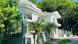 a house with palm trees in front of it at Suítes Costa Do Macacu-Garopaba in Garopaba