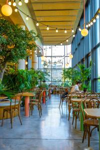 een leeg restaurant met tafels, stoelen en planten bij The People - Paris Marais in Parijs