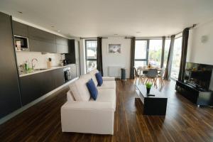 a living room with a white couch and a kitchen at Modern 2 Bed Flat in East London in London