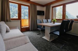 - un salon avec une table, des chaises et des fenêtres dans l'établissement Hotel Tia Apart, à Kaunertal