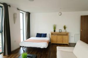 a bedroom with a bed and a table and a couch at Modern 2 Bed Flat in East London in London
