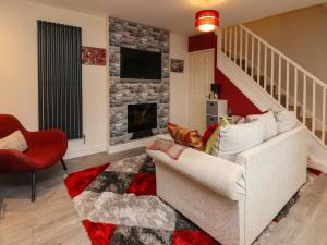 a living room with a white couch and a fireplace at 2 Stoneleigh Cottage in Wrexham