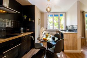 a kitchen with black cabinets and a table and chairs at Suite Madison in Villeurbanne