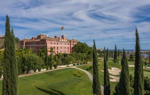 un campo de golf frente a un edificio con árboles en Anantara Villa Padierna Palace Benahavís Marbella Resort - A Leading Hotel of the World en Estepona