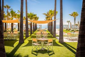 een restaurant met palmbomen en een tafel en stoelen bij Anantara Villa Padierna Palace Benahavís Marbella Resort - A Leading Hotel of the World in Estepona