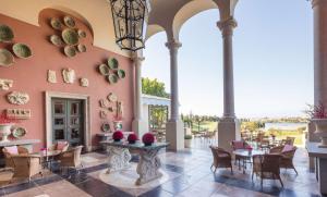 a dining room with tables and chairs and a wall of columns at Anantara Villas & Suites Marbella Benahavis in Estepona