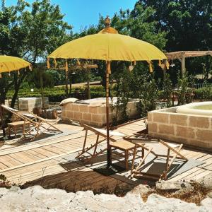 une table et des chaises sous un parasol sur une terrasse dans l'établissement B&B Luxury Villa Olimpia Home Restaurant, à Selva di Fasano