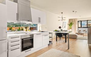 a kitchen with white cabinets and a dining table at Leilighet i topp etasje med flott stor takterrasse in Bergen